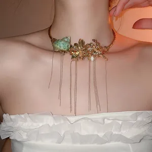 Close-up of a statement gold choker with metal flowers, conch, and long chain tassels.