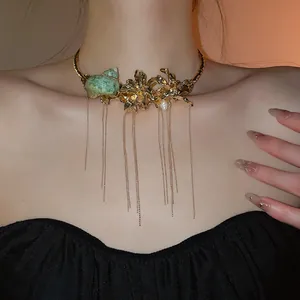 Detailed view of vintage gold flower choker with green seashell and long tassels.