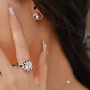 Gros plan d'un modèle portant une grande bague ronde en zircone et des boucles d'oreilles