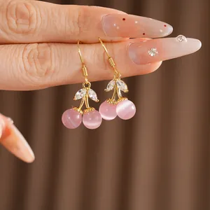 Detail view of 18k gold plated cherry ear hooks with pink cat-eye stones and zircons
