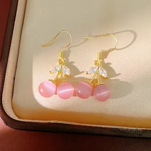 Close-up of elegant 18k gold plated cherry earrings with pink cat's eye stones
