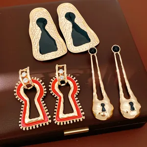 Dettaglio di orecchini d'oro geometrici di lusso con smalto rosso e nero eleganti