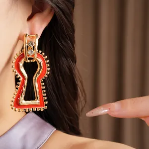 Primo piano di orecchini esagerati in oro e smalto rosso con accenti di strass