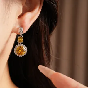 Primo piano di eleganti orecchini pendenti in zircone giallo sull'orecchio del modello