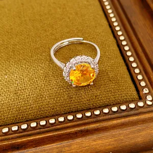Primo piano di un elegante anello in argento con zircone arancione rotondo e alone di cristalli