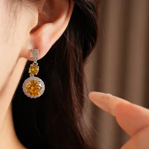 Dettaglio ravvicinato di eleganti orecchini pendenti in zirconia gialla su modella