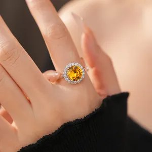 Primo piano di un elegante anello halo in zircone giallo indossato al dito per un look di lusso