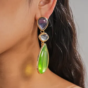 Close-up view of elegant resin teardrop earrings in purple, blue and green on a model's ear