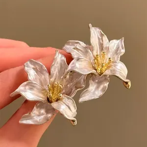 Close-up of 3D iris flower earrings with pearlescent white petals and gold stamen