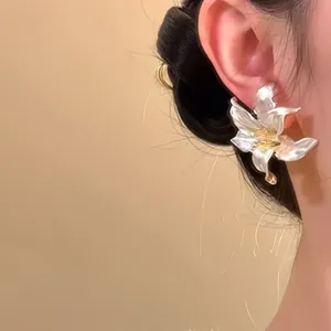 Close-up detail showing the elegant 3D iris flower earrings with pearly white petals
