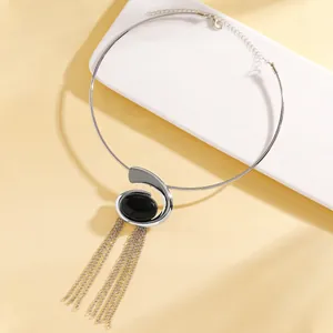 Close-up of silver snail-shaped choker necklace with black stone and long chain tassels.
