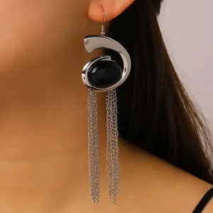 Detailed view of long silver snail earrings with black stone and chain tassels