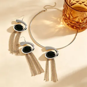 Detailed view of silver-tone snail spiral jewelry set with black stone and tassels