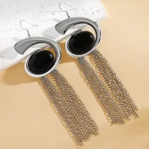 Detailed macro shot of silver snail-shaped statement earrings with long chain tassels and black stones