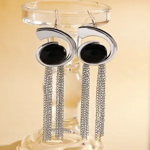 Detailed view of silver snail spiral earrings with black stones and long chain tassels