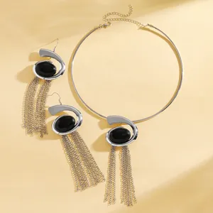 Detailed macro view of silver snail-shaped jewelry set with black stones and long tassels