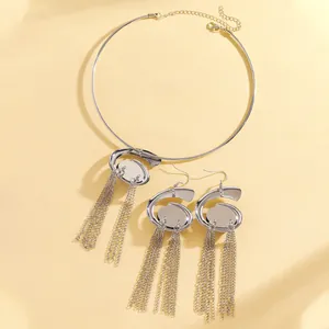 Detail of silver spiral necklace and long tassel earrings set on yellow background.
