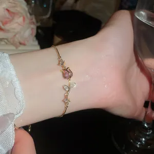 Primo piano di un elegante bracciale in oro con rosa di zircone rosa e cristalli chiari