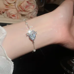 Dettaglio di un bracciale scintillante in zircone a cuore con perle sul polso