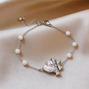 Vista dettagliata del bracciale con zircone a forma di cuore e perle su elegante raso.
