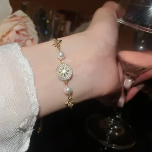 Primo piano di un braccialetto con ciondolo in zirconia e perle al polso