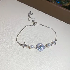 Dettaglio di un elegante bracciale in argento con zirconi scintillanti e perle bianche