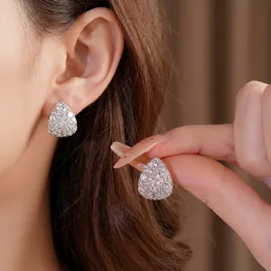 Elegant silver teardrop stud earrings with sparkling pave-set zircons on an Asian model