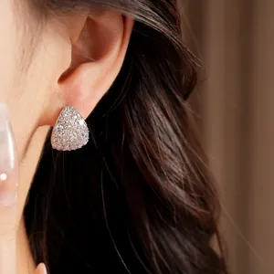 Close-up detail of elegant zircon-paved waterdrop stud earrings on model's ear