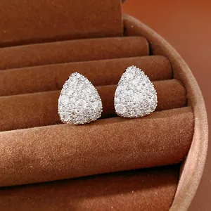 Macro detail of pear-shaped stud earrings with clear zirconia inlay on brown velvet