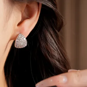 Close-up view of teardrop-shaped silver stud earrings encrusted with sparkling zirconia