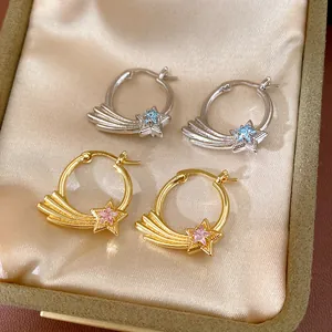 Detailed macro view of gold and silver shooting star hoop earrings with zirconia