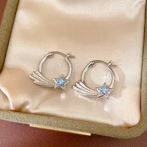 Detailed view of silver-toned hoop earrings featuring a blue zircon shooting star motif