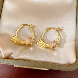 Close-up of gold shooting star hoop earrings with pink zircon in a satin jewelry box