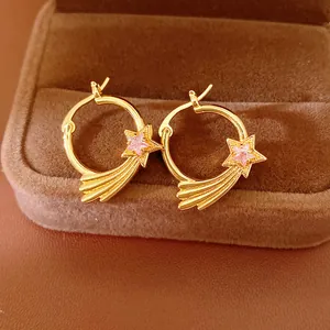 Macro view of gold star hoop earrings with pink zircon stone on velvet box