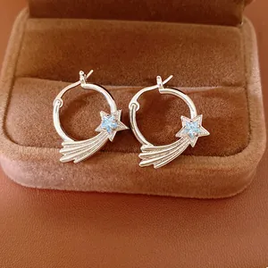 Macro view of silver-tone shooting star hoop earrings set with light blue zircon stones
