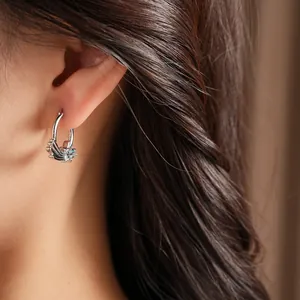 Close-up of silver-toned star ear hoop featuring light blue zircon stones on model ear.