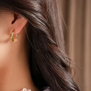 Close-up of a model wearing a gold hoop earring with a pink zircon star detail.