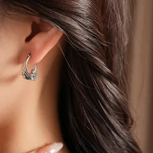 Detailed close-up of a minimalist silver star hoop earring with blue zircon on a model