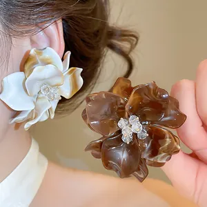 Detailed macro shot of acrylic marbled flower earrings with crystal bead centers on model