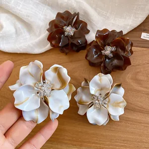 Close-up of elegant acrylic flower stud earrings with crystal beaded centers.