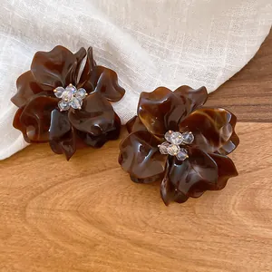 Detailed close-up of brown acrylic flower earrings with sparkling crystal bead centers