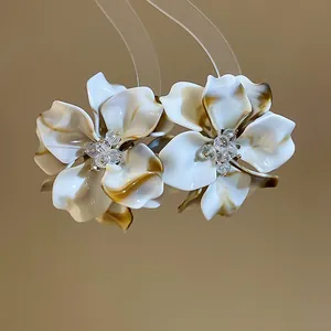 Detailed macro view of elegant white acrylic flower earrings with crystal beaded centers.