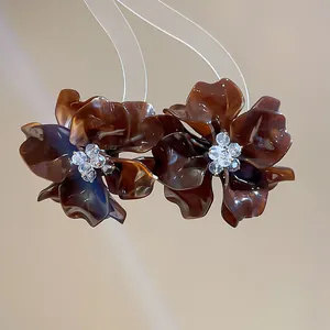 Macro view of brown tortoise shell acrylic flower earrings with crystal centers