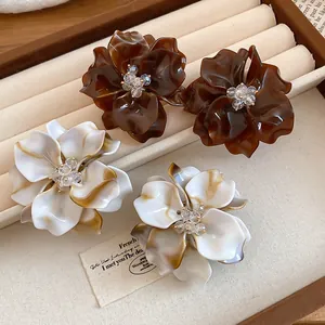 Detailed macro view of acrylic flower stud earrings with crystal beads and marble texture