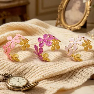 Primo piano di tre bracciali a fiori dorati in rosa e magenta su tessuto a maglia