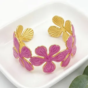 Primo piano di bracciale rigido dorato con fiori in smalto rosa