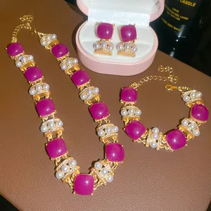 Close-up of vintage jewelry set with purple resin squares, pearls, and rhinestones.