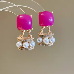 Detailed shot of vintage earrings with magenta resin and pearl inlay