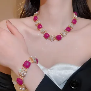Close-up of vintage jewelry set with magenta resin stones and pearls on a model