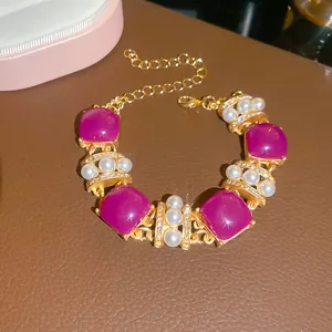 Close-up of vintage gold bracelet with magenta square resin stones and pearls